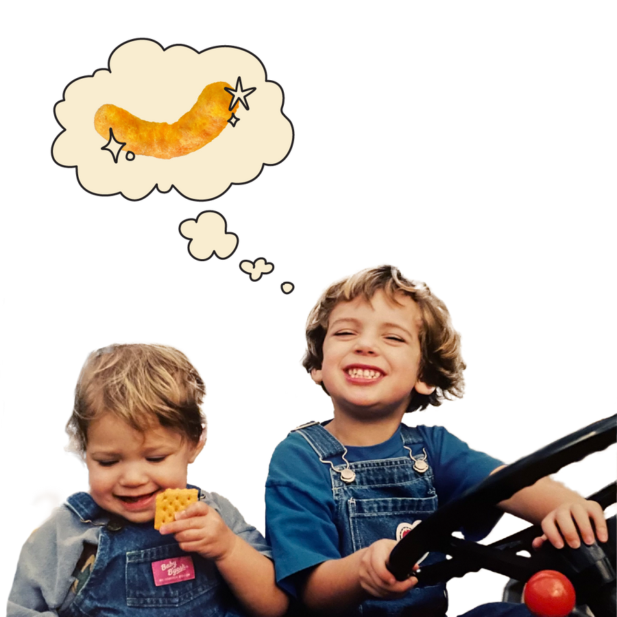 Two children playing with a toy truck with a thought bubble above them depicting an ancient grain cheddar puff.