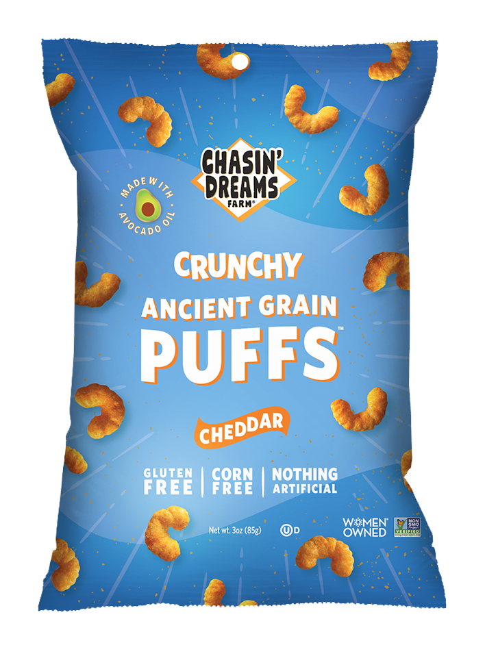 Chasin' Dreams Farm Crunchy Ancient Grain Cheddar Puffs 3oz front of package. Blue bag with white stripes and speckles and orange puffs around the border.